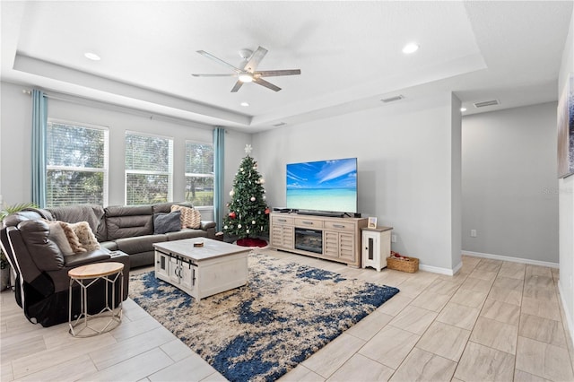 living room featuring a raised ceiling and ceiling fan