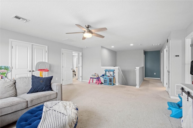 game room featuring ceiling fan, light colored carpet, and a textured ceiling