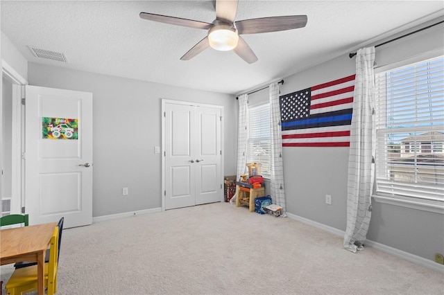 game room with ceiling fan, light carpet, and a textured ceiling