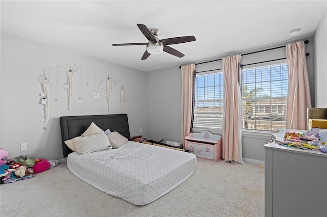 bedroom featuring a textured ceiling, light colored carpet, and ceiling fan