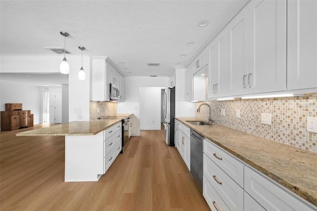 kitchen featuring pendant lighting, light stone counters, white cabinetry, and stainless steel appliances