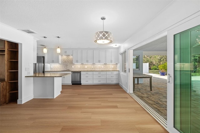 kitchen featuring pendant lighting, white cabinetry, kitchen peninsula, stainless steel appliances, and light hardwood / wood-style flooring