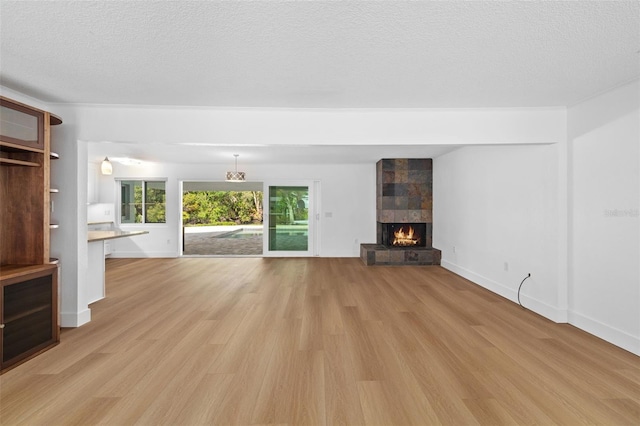 unfurnished living room featuring a large fireplace, a textured ceiling, and light wood-type flooring