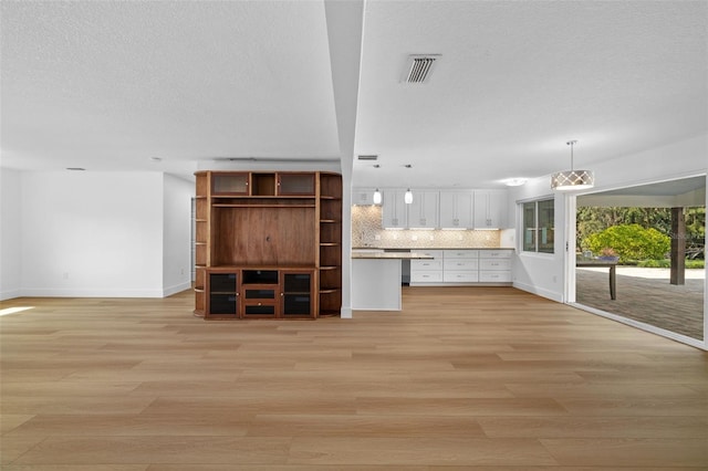 unfurnished living room featuring light hardwood / wood-style flooring and a textured ceiling