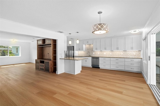 kitchen featuring stainless steel appliances, white cabinetry, tasteful backsplash, and decorative light fixtures