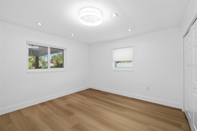 unfurnished room featuring a textured ceiling and light wood-type flooring