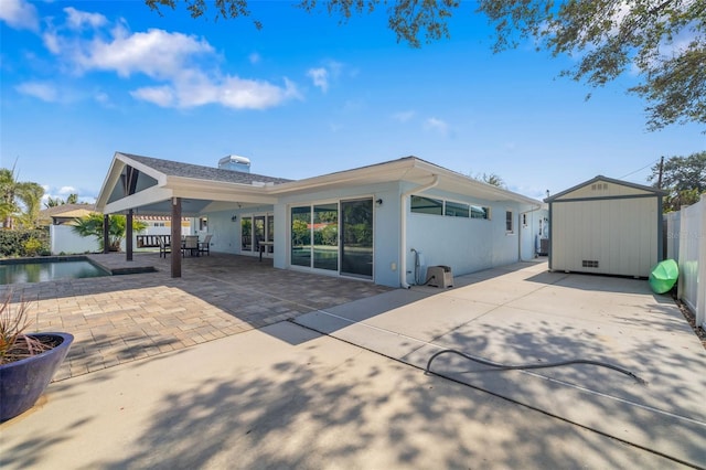 back of property with a shed and a patio area