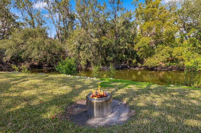 view of yard with an outdoor fire pit and a water view