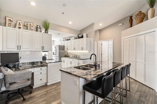 kitchen featuring white cabinetry, sink, stainless steel fridge, and a kitchen bar