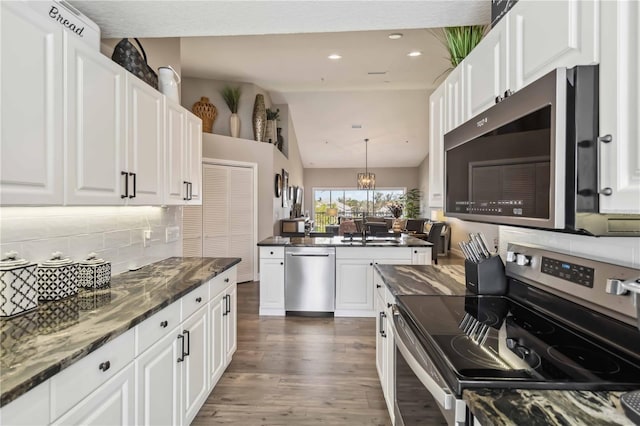 kitchen with appliances with stainless steel finishes, white cabinets, and decorative light fixtures