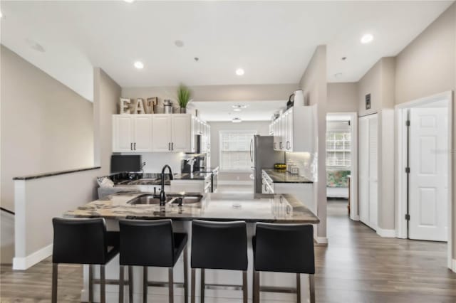 kitchen with stainless steel refrigerator, a wealth of natural light, sink, and white cabinets