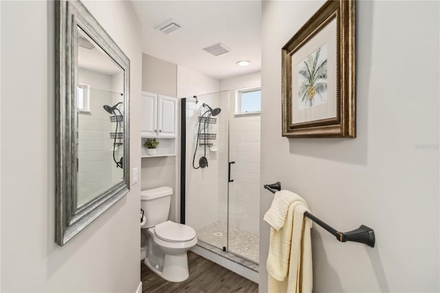 bathroom with toilet, hardwood / wood-style floors, and a tile shower