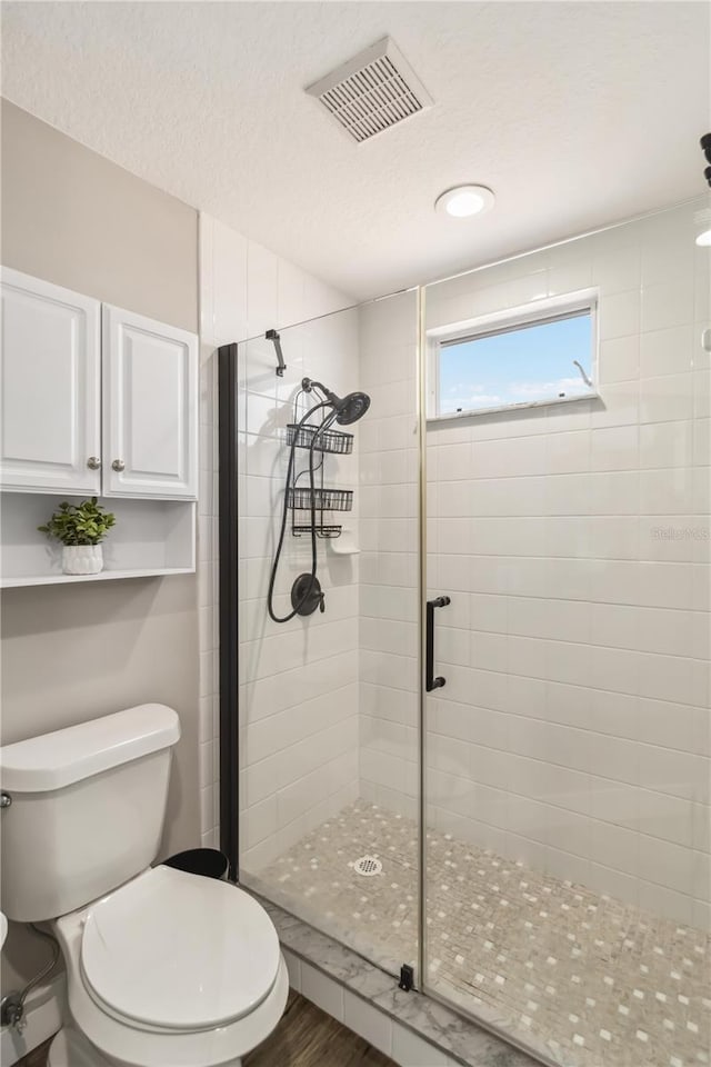 bathroom featuring an enclosed shower, hardwood / wood-style flooring, a textured ceiling, and toilet