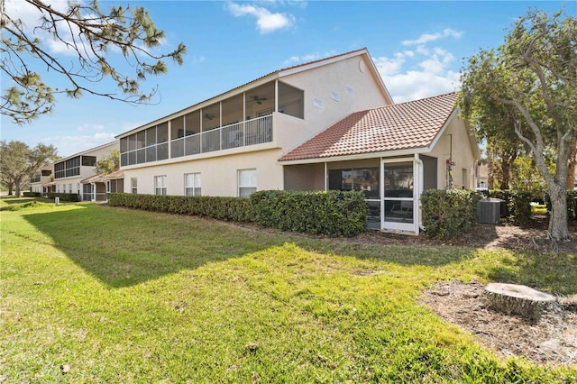 rear view of house with a sunroom, central AC unit, and a lawn