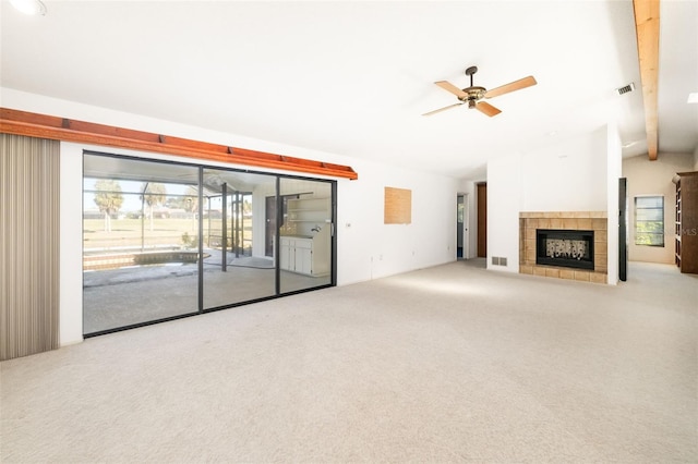 unfurnished living room featuring vaulted ceiling, ceiling fan, carpet floors, and a tile fireplace