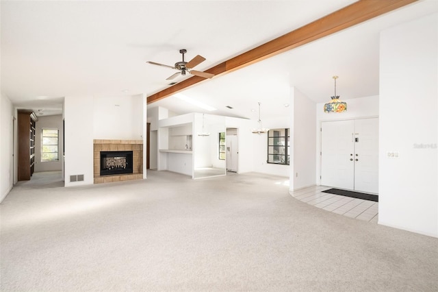 unfurnished living room featuring vaulted ceiling with beams, light colored carpet, a fireplace, and ceiling fan