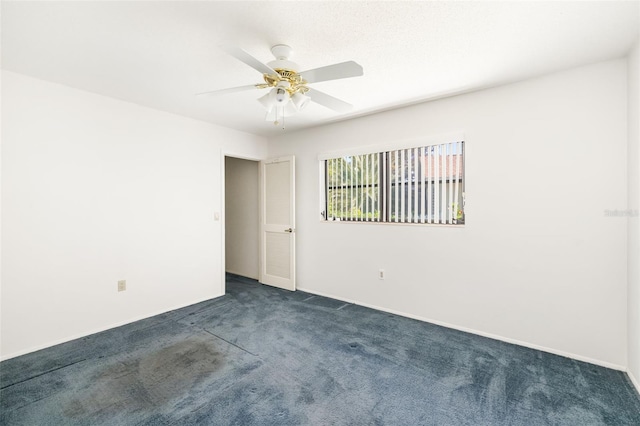 empty room with ceiling fan and dark carpet