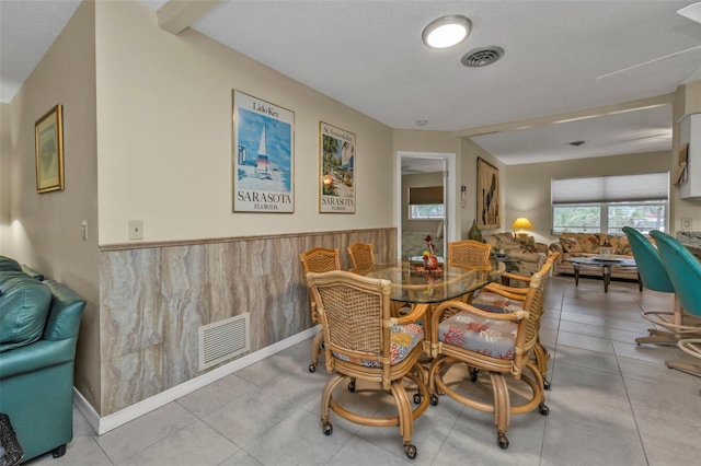 dining room with light tile patterned flooring and wood walls