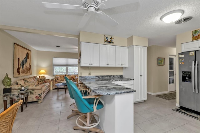 kitchen with white cabinetry, kitchen peninsula, light tile patterned floors, and stainless steel fridge with ice dispenser