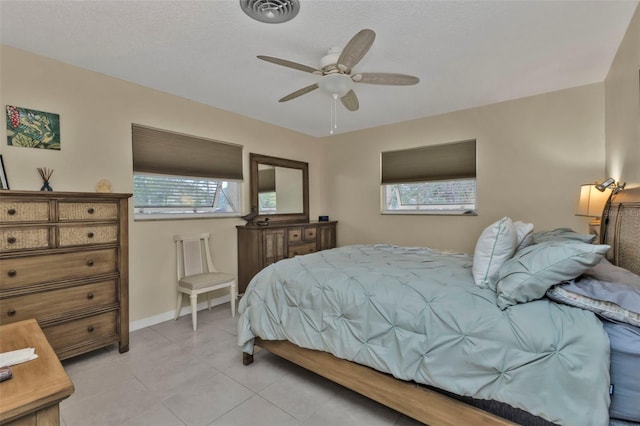 tiled bedroom featuring multiple windows, ceiling fan, and a textured ceiling