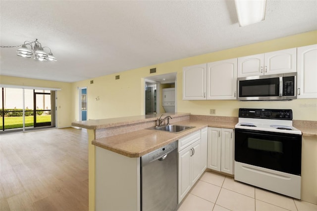 kitchen with stainless steel appliances, sink, white cabinets, and kitchen peninsula