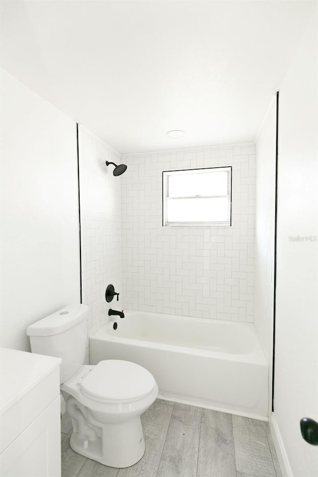 full bathroom with vanity, tiled shower / bath combo, toilet, and hardwood / wood-style flooring