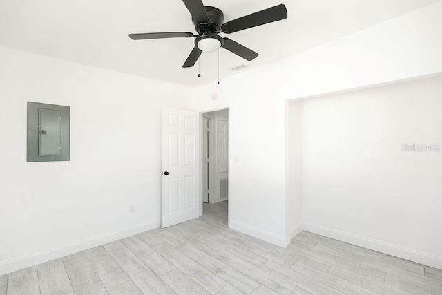 empty room featuring electric panel, ceiling fan, and light hardwood / wood-style flooring