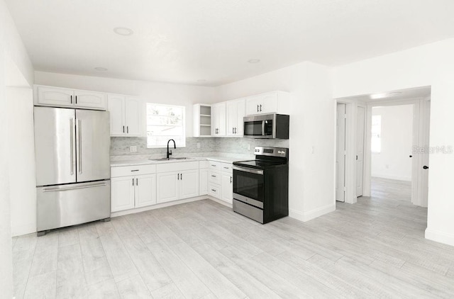 kitchen with white cabinetry, stainless steel appliances, sink, and backsplash