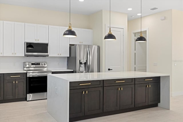 kitchen featuring pendant lighting, tasteful backsplash, white cabinetry, a center island, and stainless steel appliances