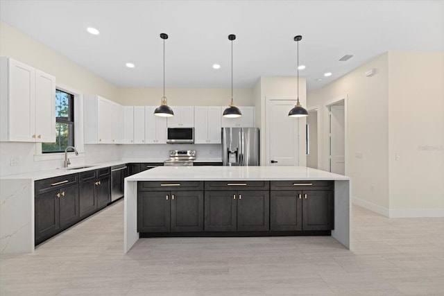 kitchen featuring white cabinetry, appliances with stainless steel finishes, a center island, and sink