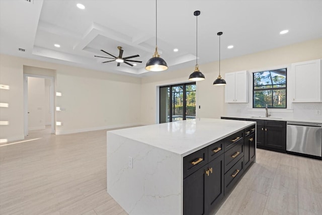 kitchen with dishwasher, sink, a kitchen island, and white cabinets