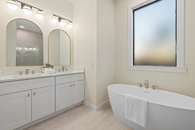 bathroom with hardwood / wood-style floors, vanity, and a washtub