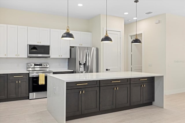 kitchen featuring hanging light fixtures, appliances with stainless steel finishes, a center island, and white cabinets