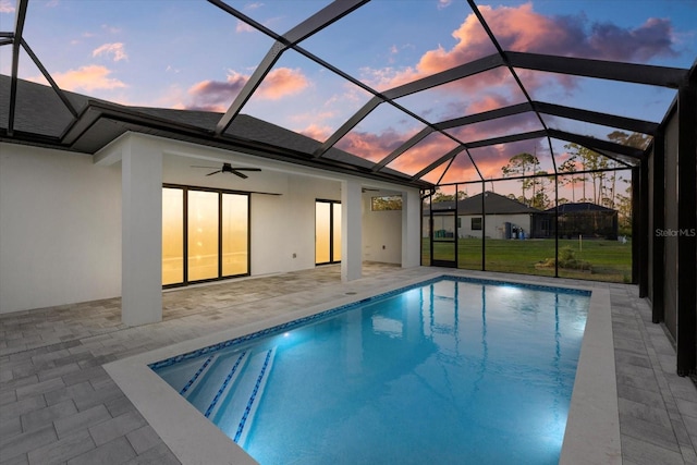 pool at dusk with a patio, a lanai, and ceiling fan