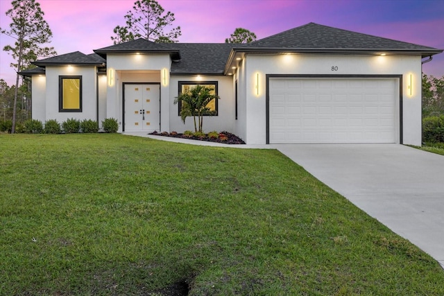 view of front of home with a garage and a lawn