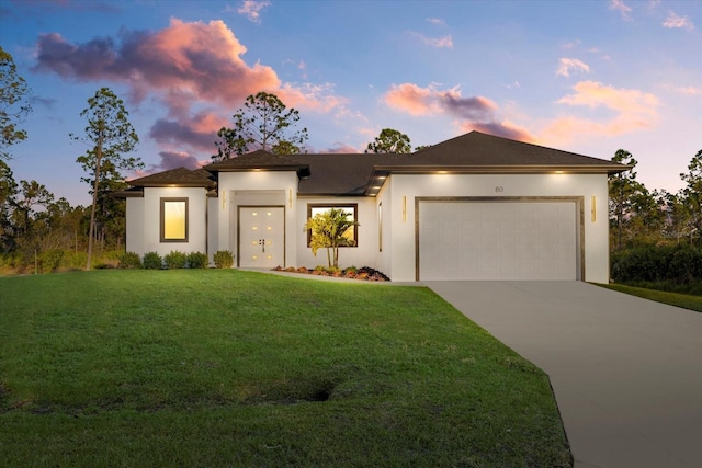 prairie-style home featuring a garage and a lawn