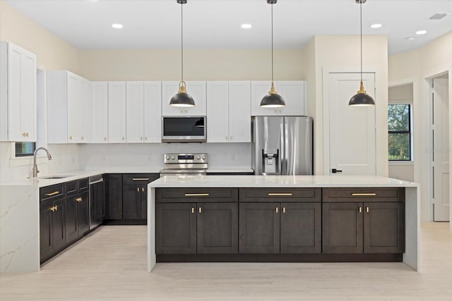 kitchen featuring pendant lighting, sink, white cabinets, and appliances with stainless steel finishes