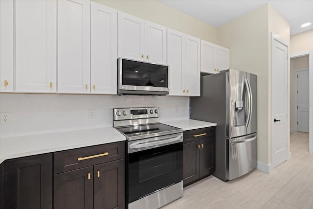 kitchen with backsplash, appliances with stainless steel finishes, light stone countertops, and white cabinets