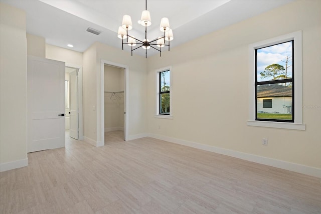 spare room with an inviting chandelier and light hardwood / wood-style floors