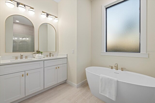 bathroom with hardwood / wood-style flooring, a tub to relax in, and vanity