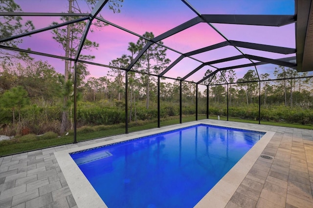 pool at dusk with a patio and glass enclosure