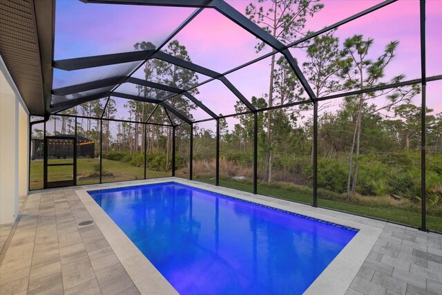 pool at dusk featuring a patio area and glass enclosure