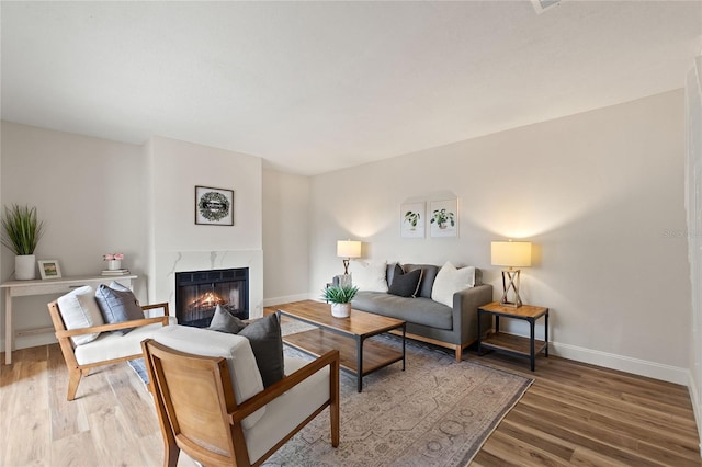 living room with a high end fireplace and hardwood / wood-style floors