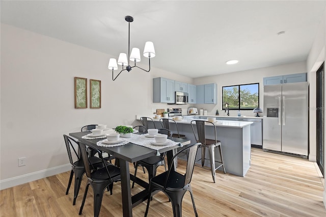 dining room featuring an inviting chandelier, sink, and light hardwood / wood-style flooring