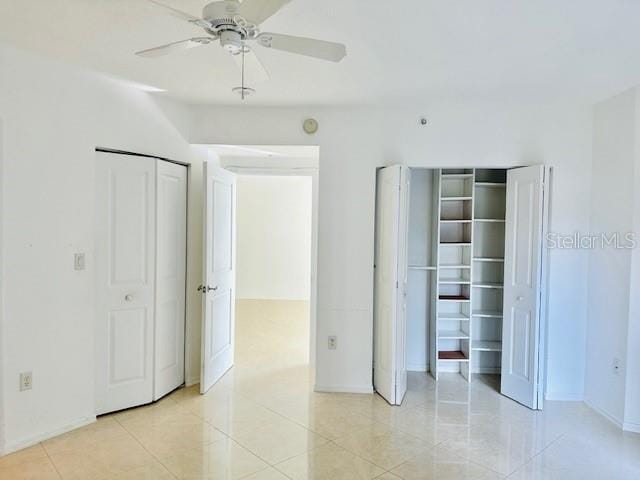 unfurnished bedroom featuring two closets, ceiling fan, and light tile patterned flooring