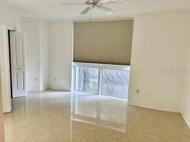 spare room with ceiling fan and light tile patterned flooring