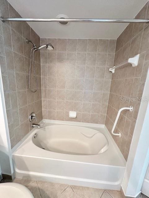 bathroom with tiled shower / bath, tile patterned floors, and toilet