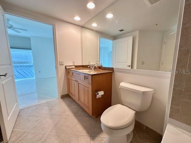 bathroom with tile patterned floors, toilet, vanity, and a tile shower