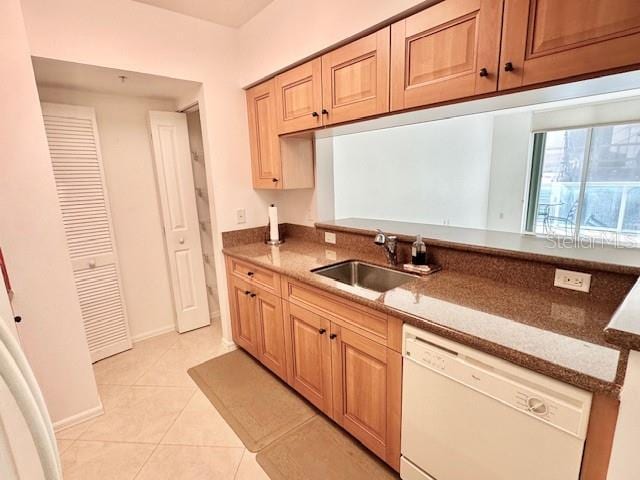 kitchen featuring stone counters, light tile patterned flooring, sink, and white dishwasher