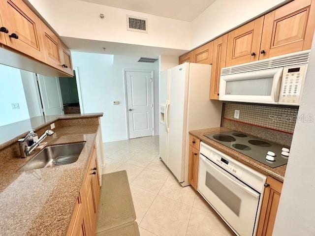 kitchen featuring sink, stone countertops, light tile patterned floors, white appliances, and decorative backsplash